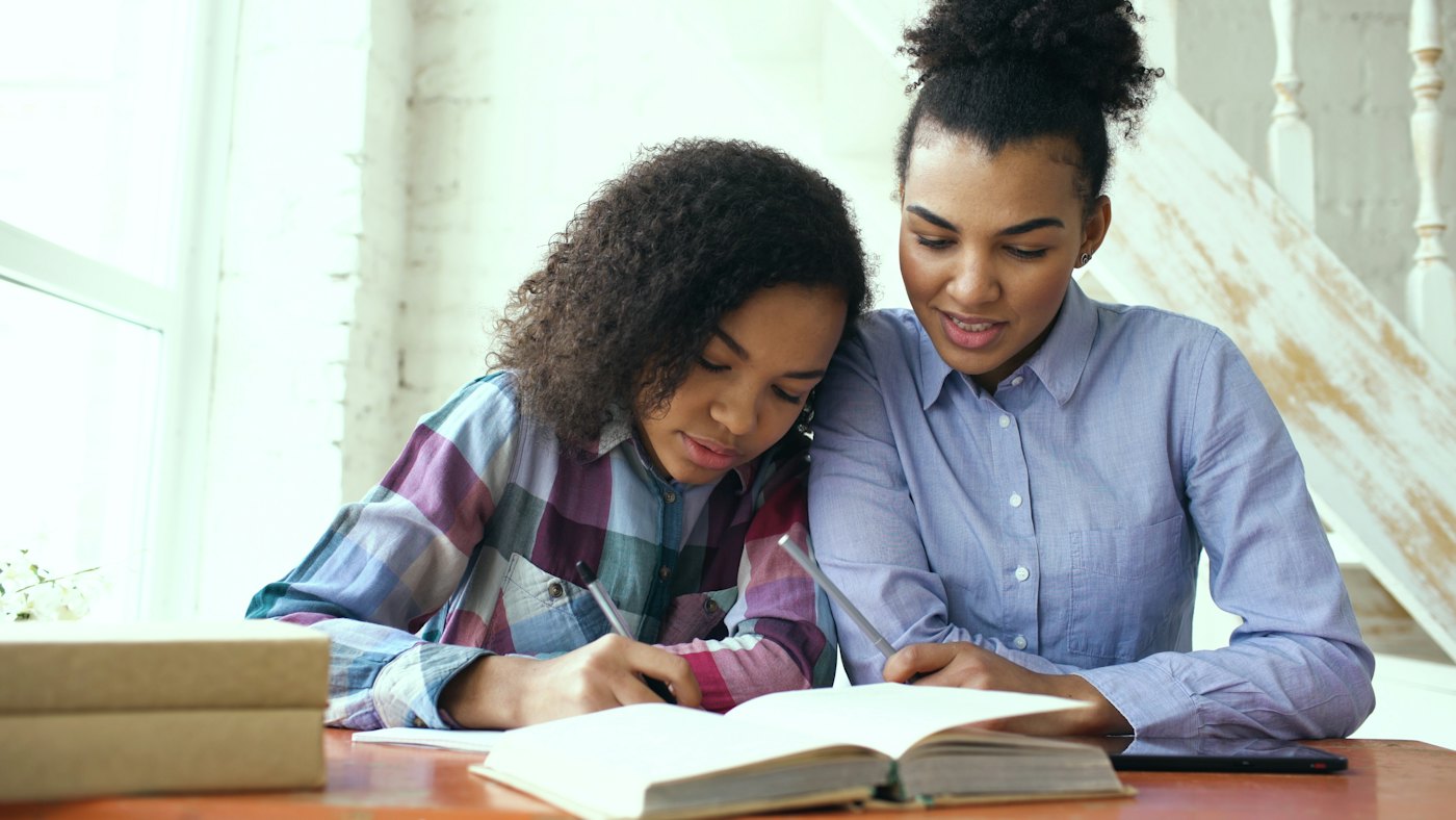 Twee jongeren kijken samen in een boek